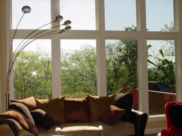 Sunlight filters through large home windows, showcasing clear views of a green landscape